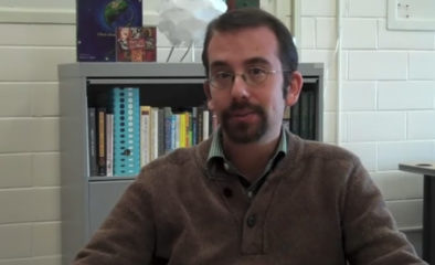 Professor Brian Grossman seated in front of a book case