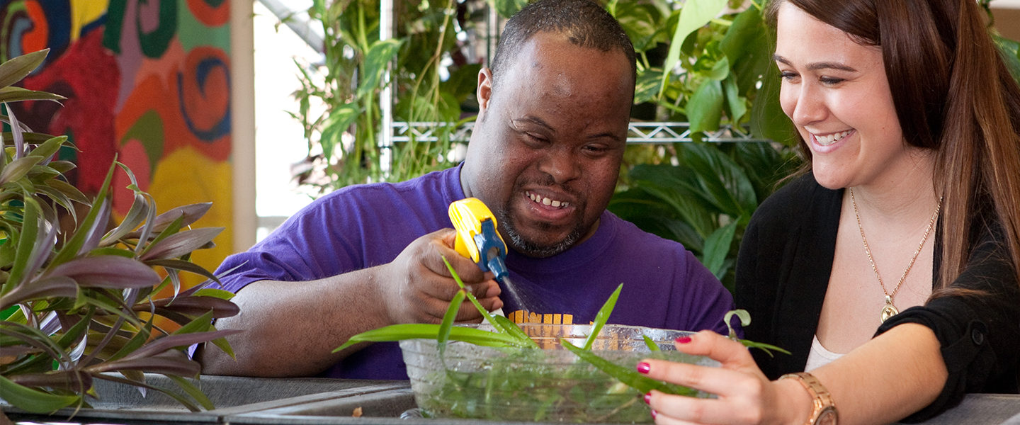 Woman working with plants with African-American man with disabilities