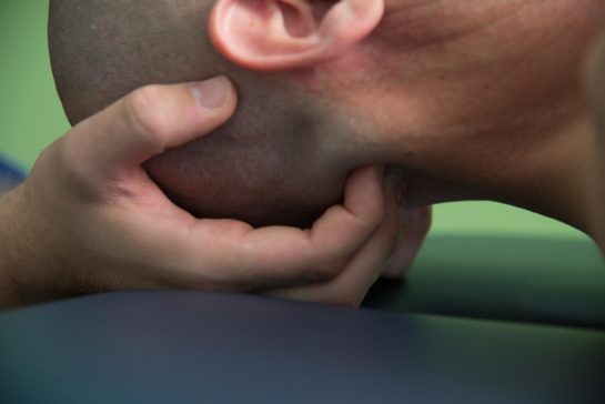 Hands of a physical therapist manipulating a patient's neck