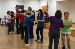 David Marquez and dance instructor teaching class of older Latinos how to dance